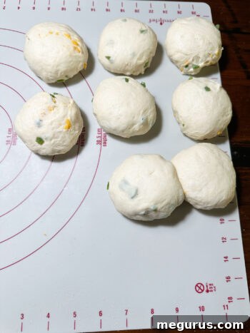 Dough pieces after being expertly rolled into smooth, tight balls, ready for shaping