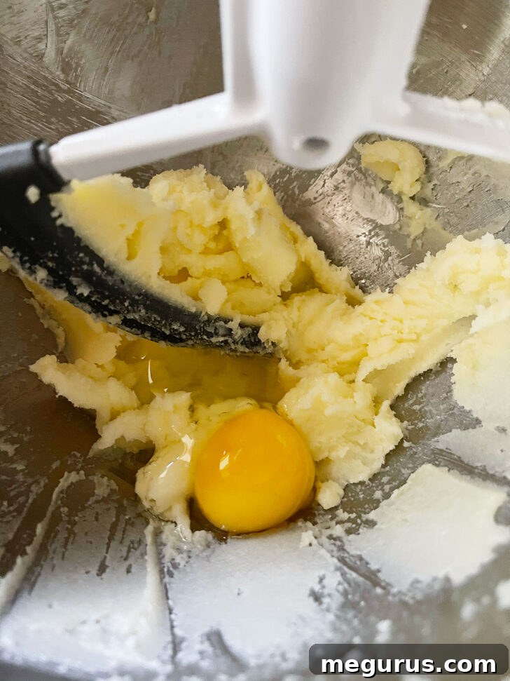 An egg being added to the creamed butter and sugar mixture
