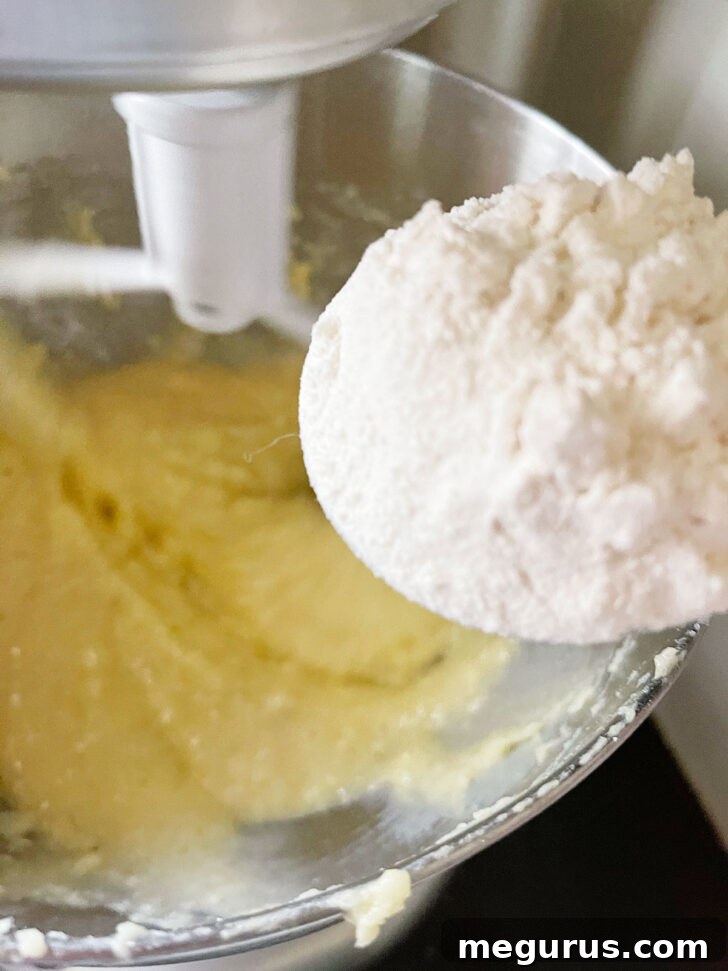 Adding dry flour mixture to the wet batter in the mixing bowl