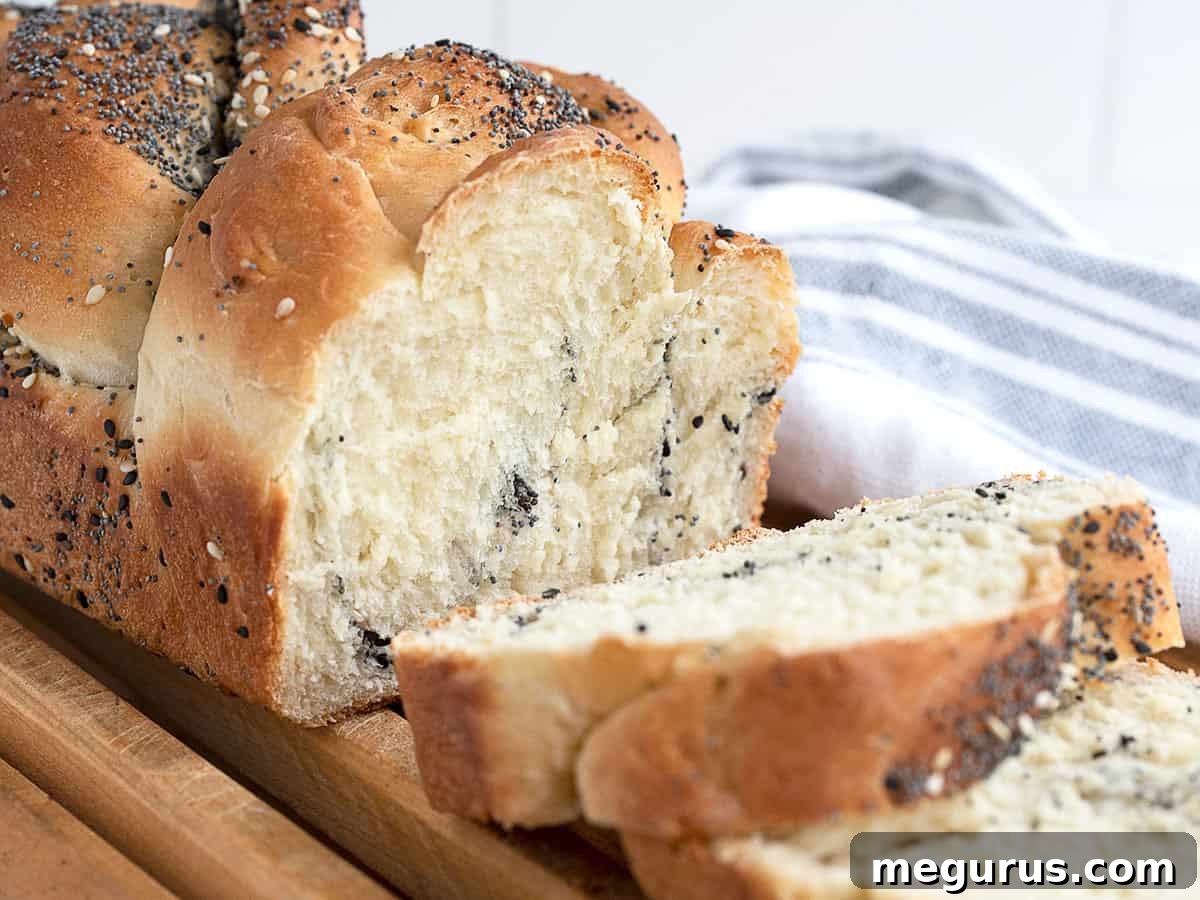 Everything Bread sliced on cooling rack, showcasing golden crust and abundant seeds.