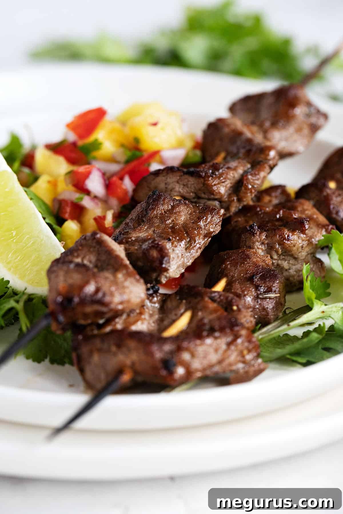 jerk pork skewers on plate with pineapple salsa