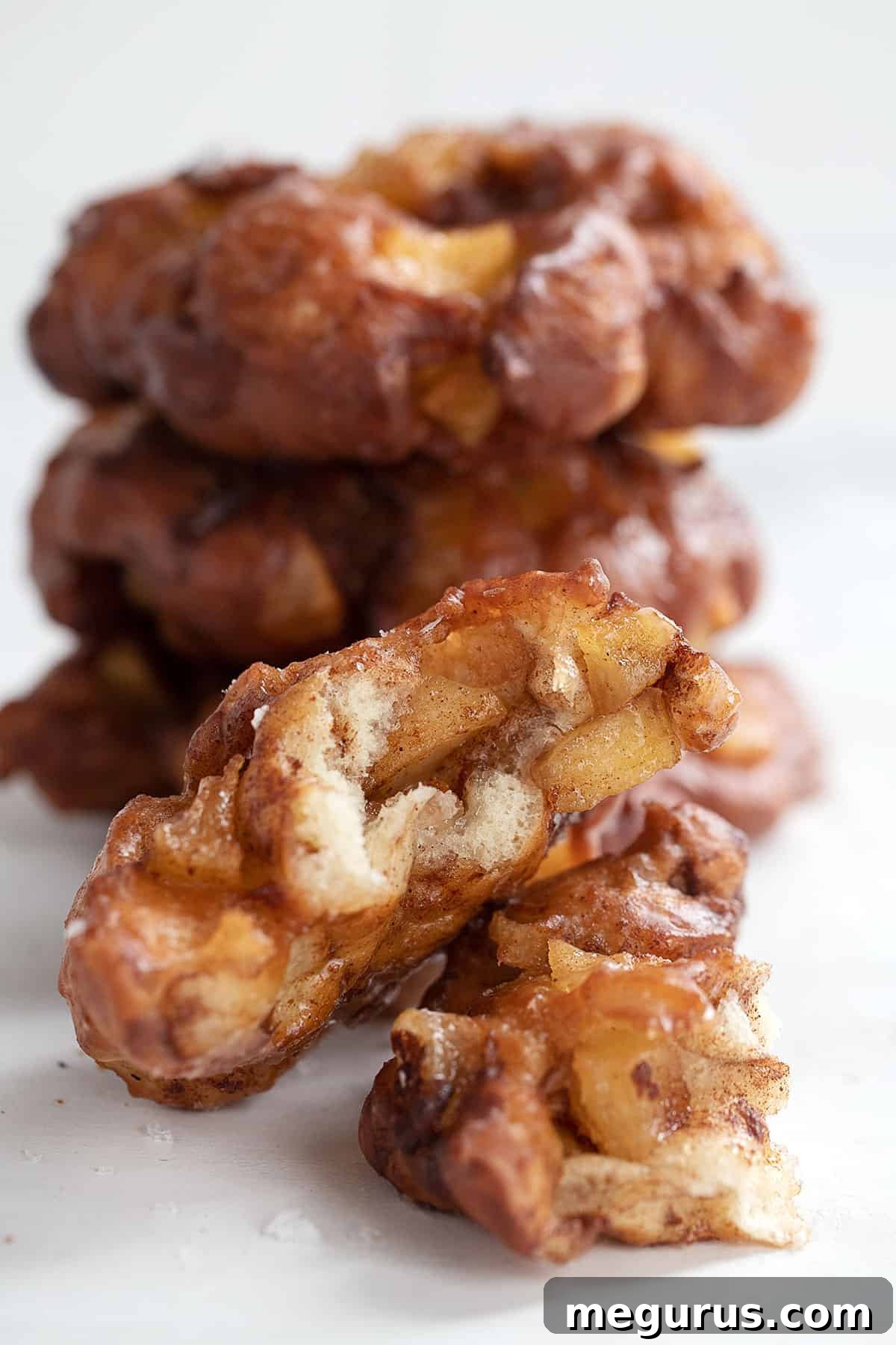 apple fritter yeast doughnuts stacked with one broken open