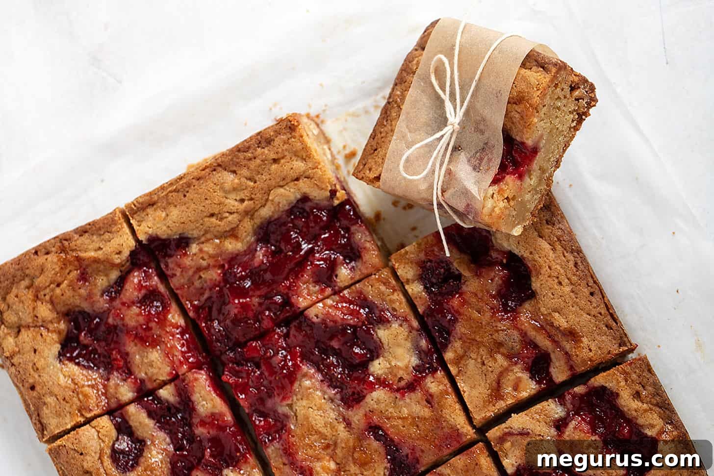 Freshly baked strawberry and white chocolate blondies sliced on parchment paper, ready to be served.