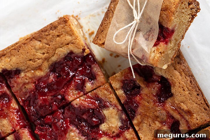 Strawberry and white chocolate blondies sliced into squares, showcasing the swirled compote and white chocolate chunks.