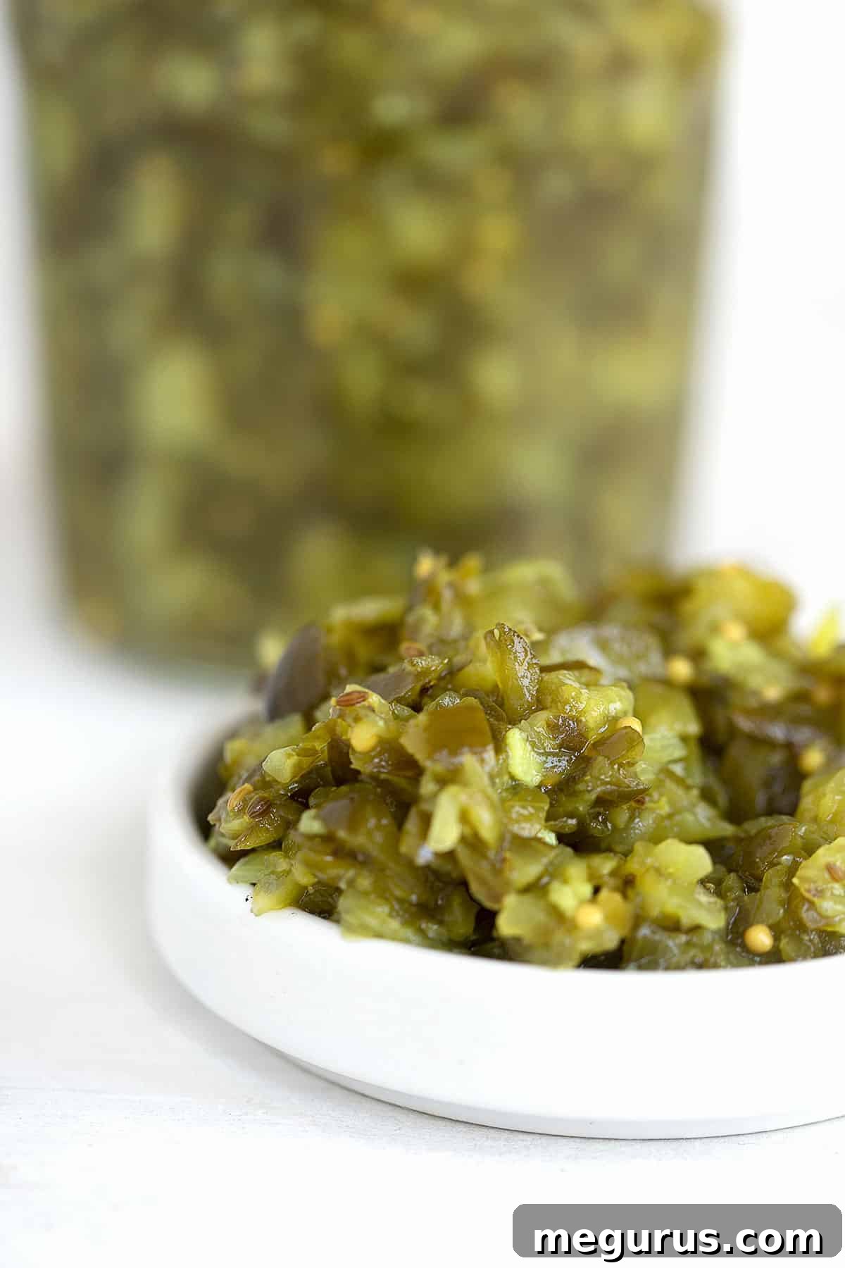 dill pickle relish in white bowl with jar of relish behind