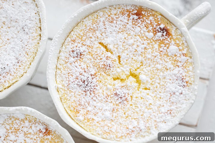 Golden-brown lemon pudding cakes on a decorative serving stand, dusted with powdered sugar.