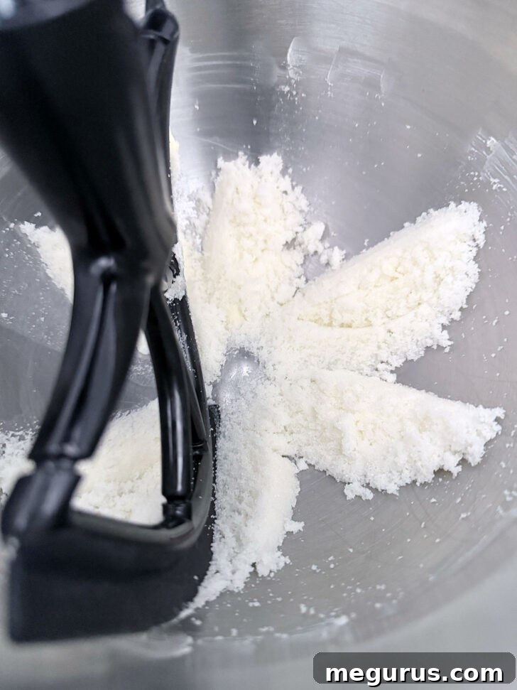 Creamy butter and granulated sugar thoroughly mixed in a stand mixer bowl, showing a lightened, sandy texture.