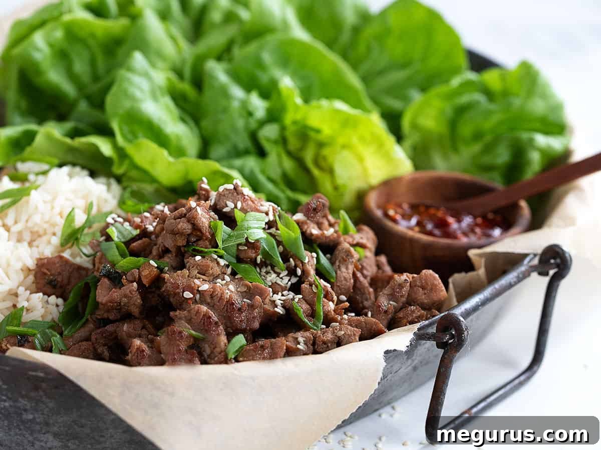 Pork bulgogi on a platter with rice and crisp lettuce leaves, ready for making wraps.