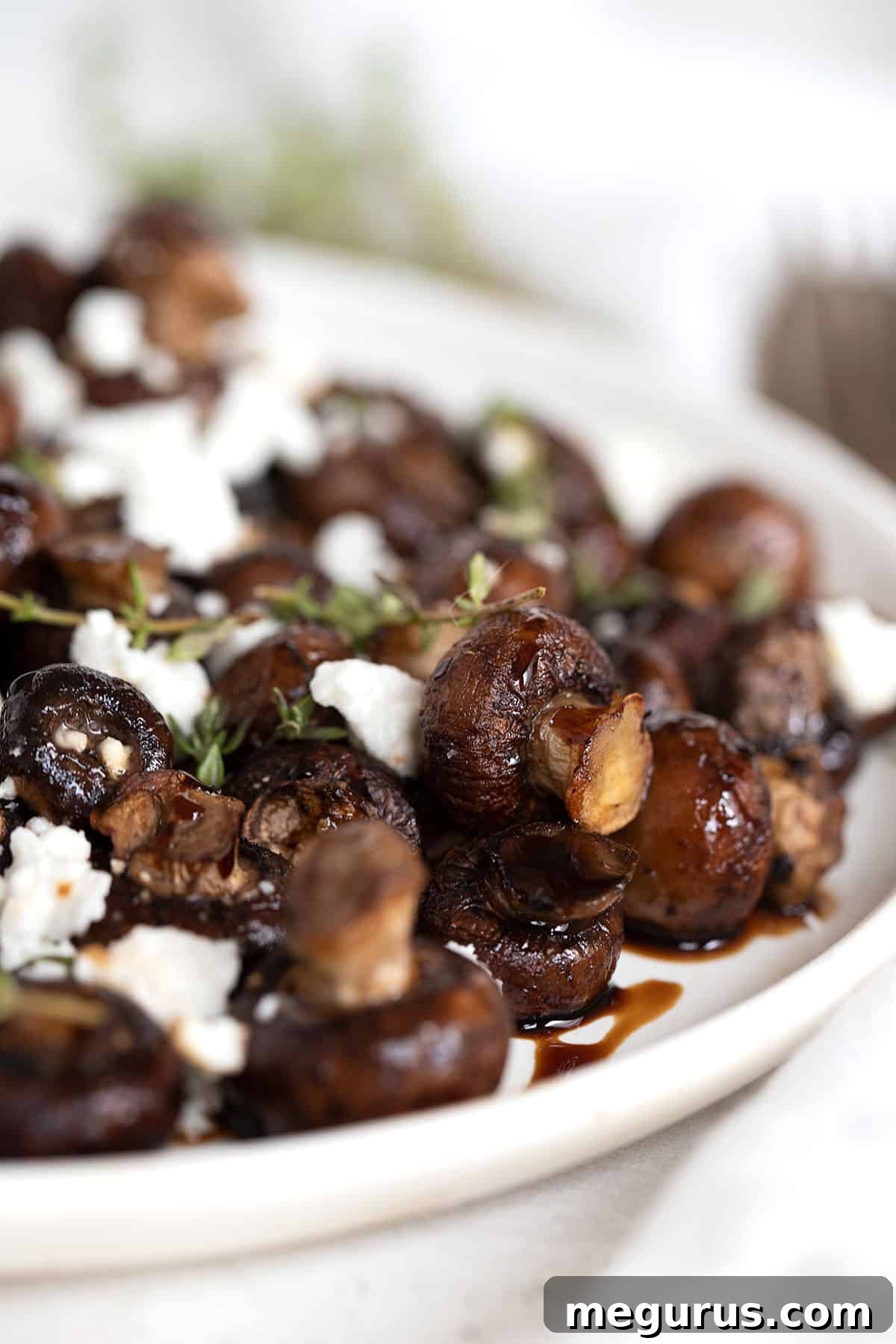 Air-fried mushrooms served in a bowl with balsamic glaze and crumbled goat cheese.