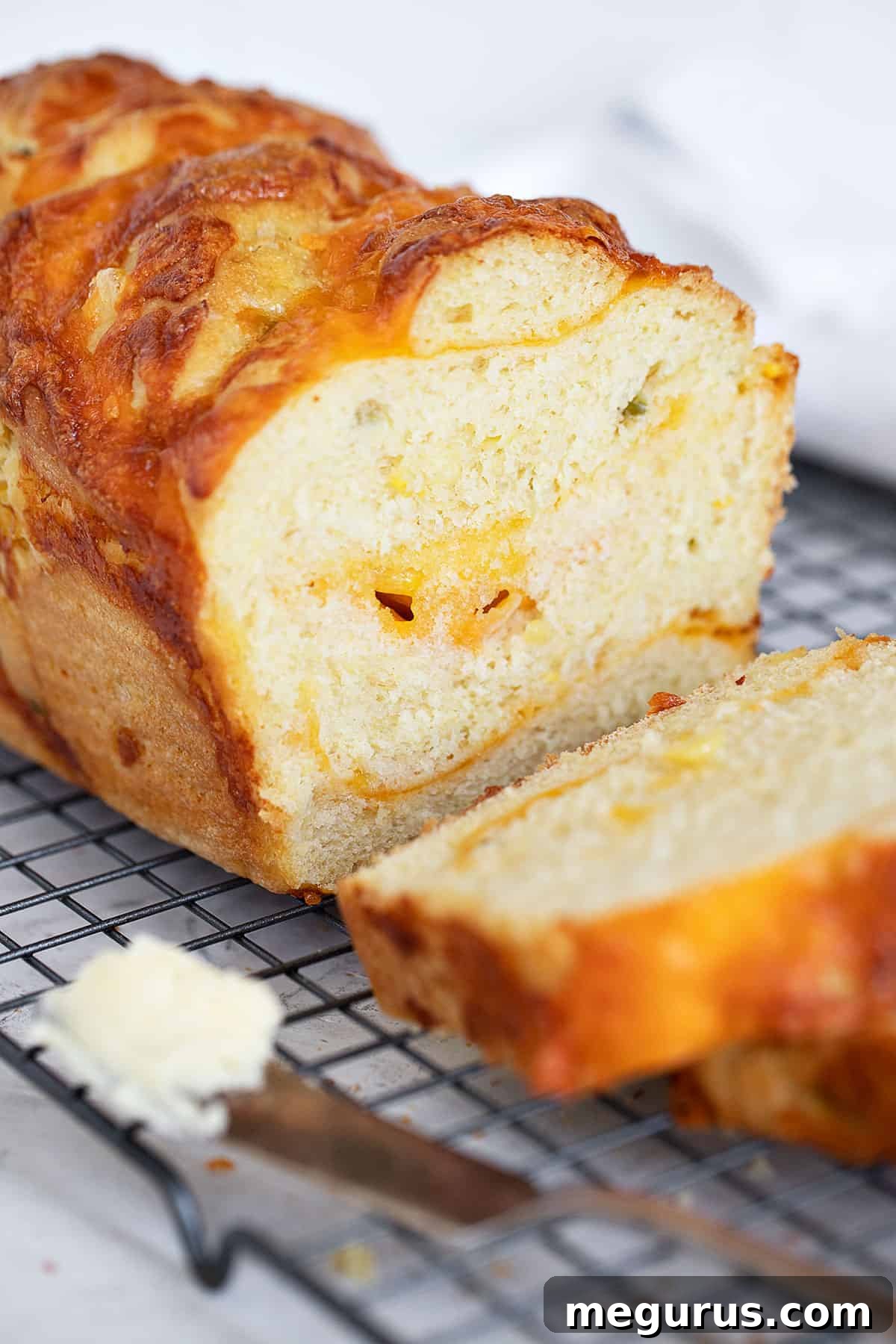 Detail shot of sliced jalapeno corn cheese bread with visible corn and cheese, cooling on a rack.