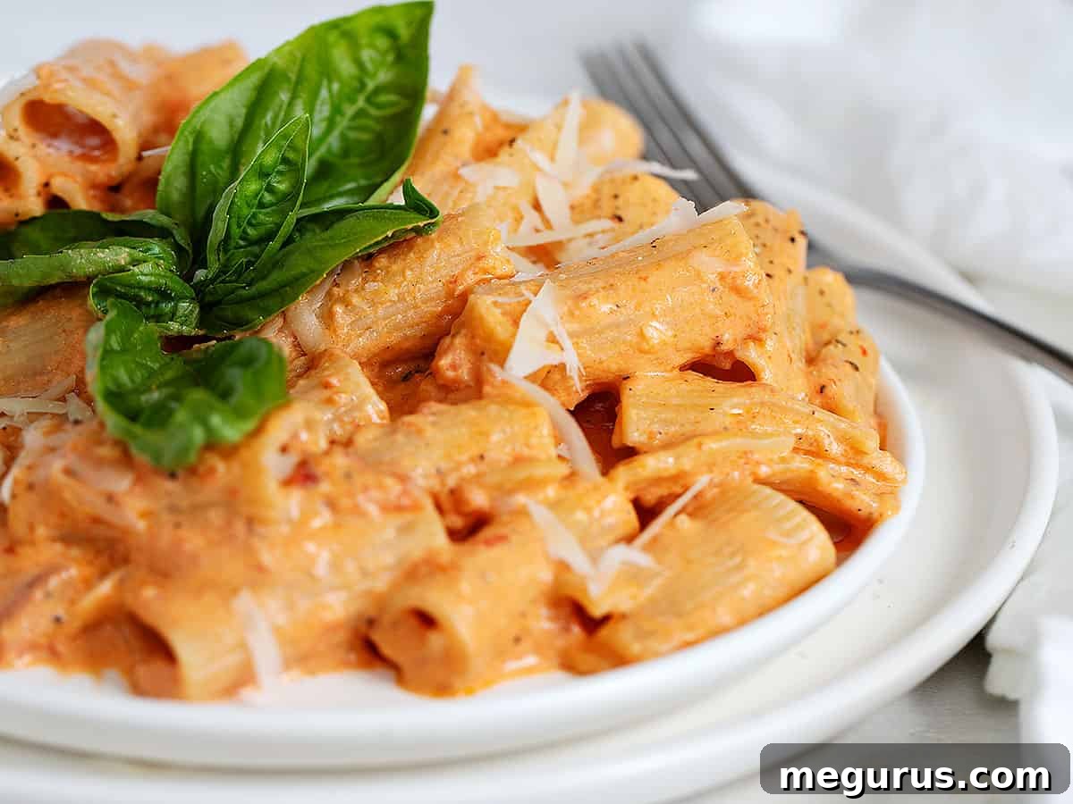 Creamy Roasted Red Pepper Pasta with fresh basil garnish on a rustic plate
