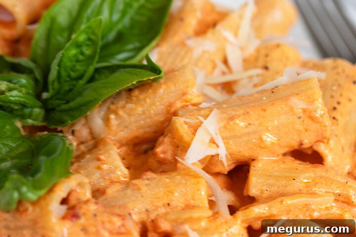 creamy roasted red pepper pasta on plate with basil leaves