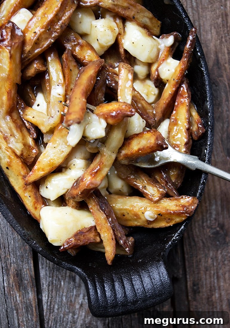 Poutine ingredients: fries, gravy, and cheese curds on a white plate
