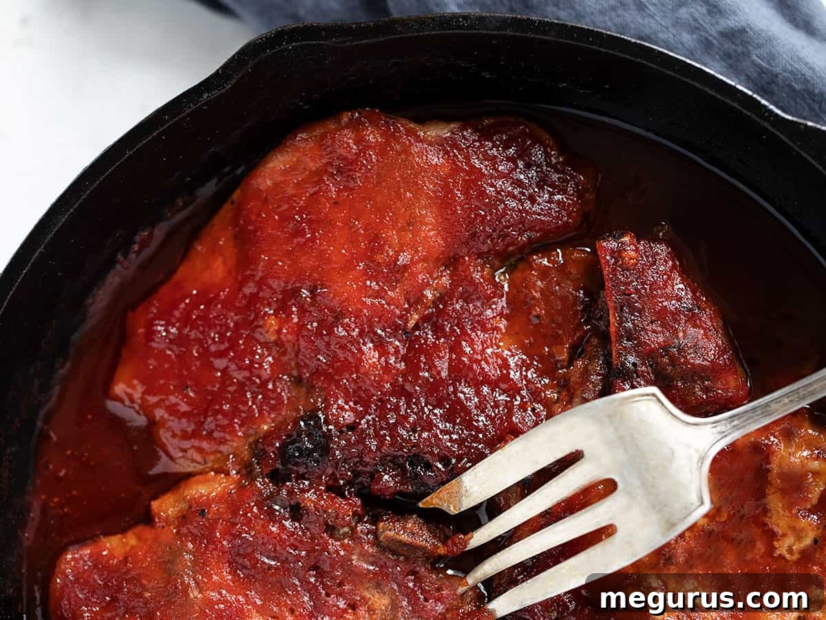 baked bbq pork chops in cast iron skillet, golden brown and saucy