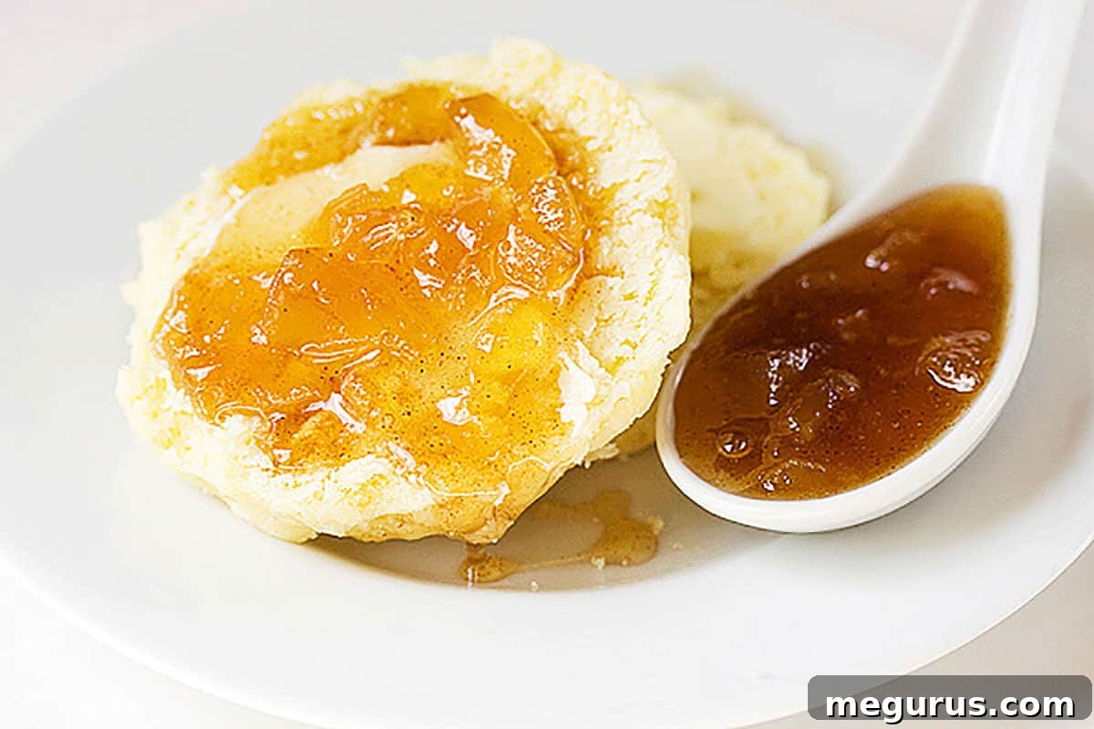 Delicious apple pie jam spread generously on a warm biscuit, ready to be enjoyed.