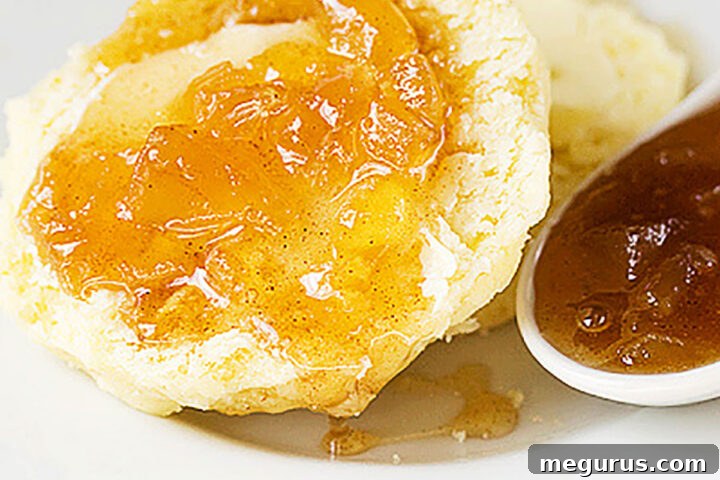 Apple Pie Jam served on a golden biscuit, showcasing its rich texture and color.