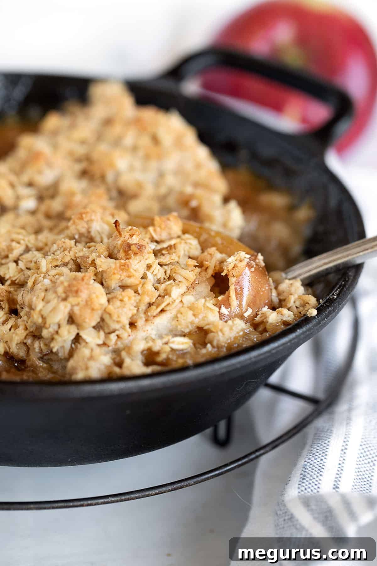 Baked apples with oat crumble in a cast iron skillet, ready to serve as a comforting fall dessert.