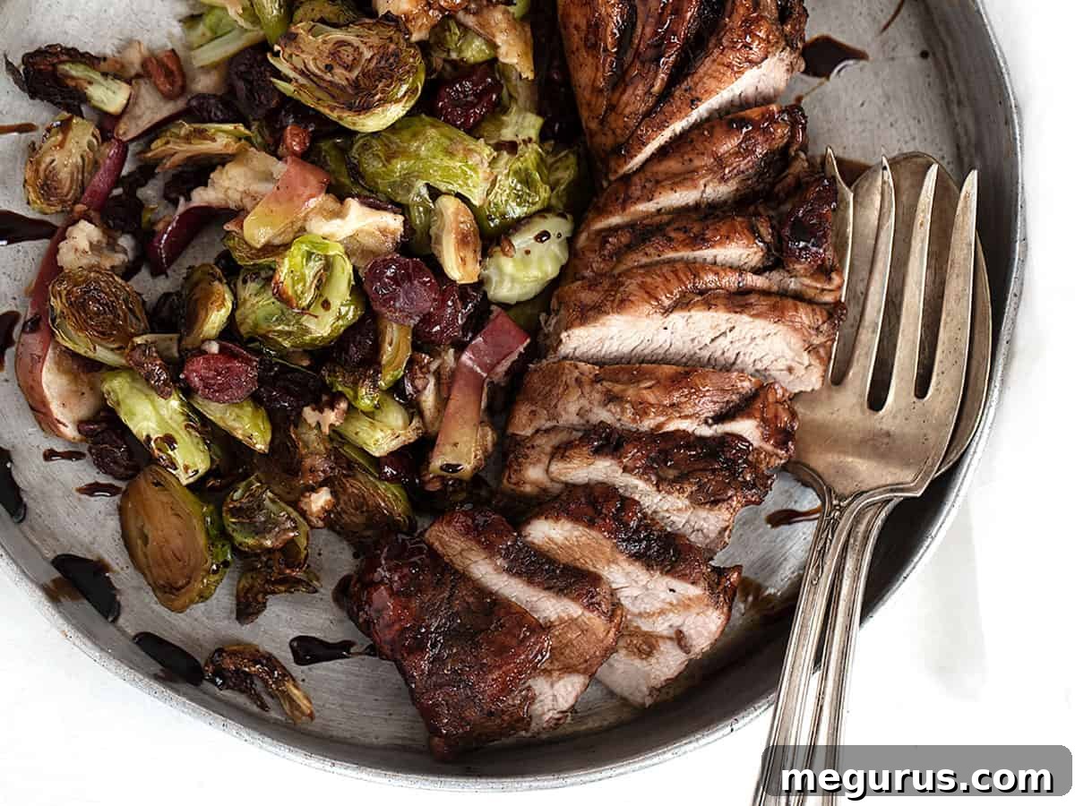 pork tenderloin sliced on platter with Brussels sprouts, apples, and cranberries