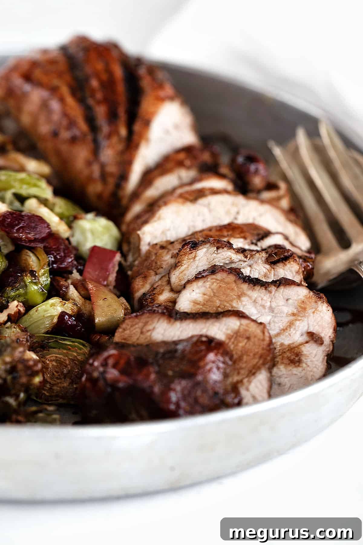 pork tenderloin on serving platter with Brussels sprouts, apples, and cranberries