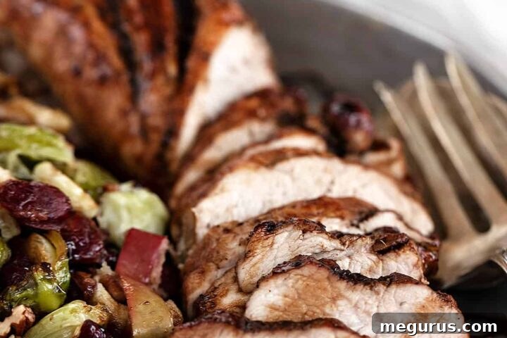 pork tenderloin sliced on platter with Brussels sprours, apples, and cranberries
