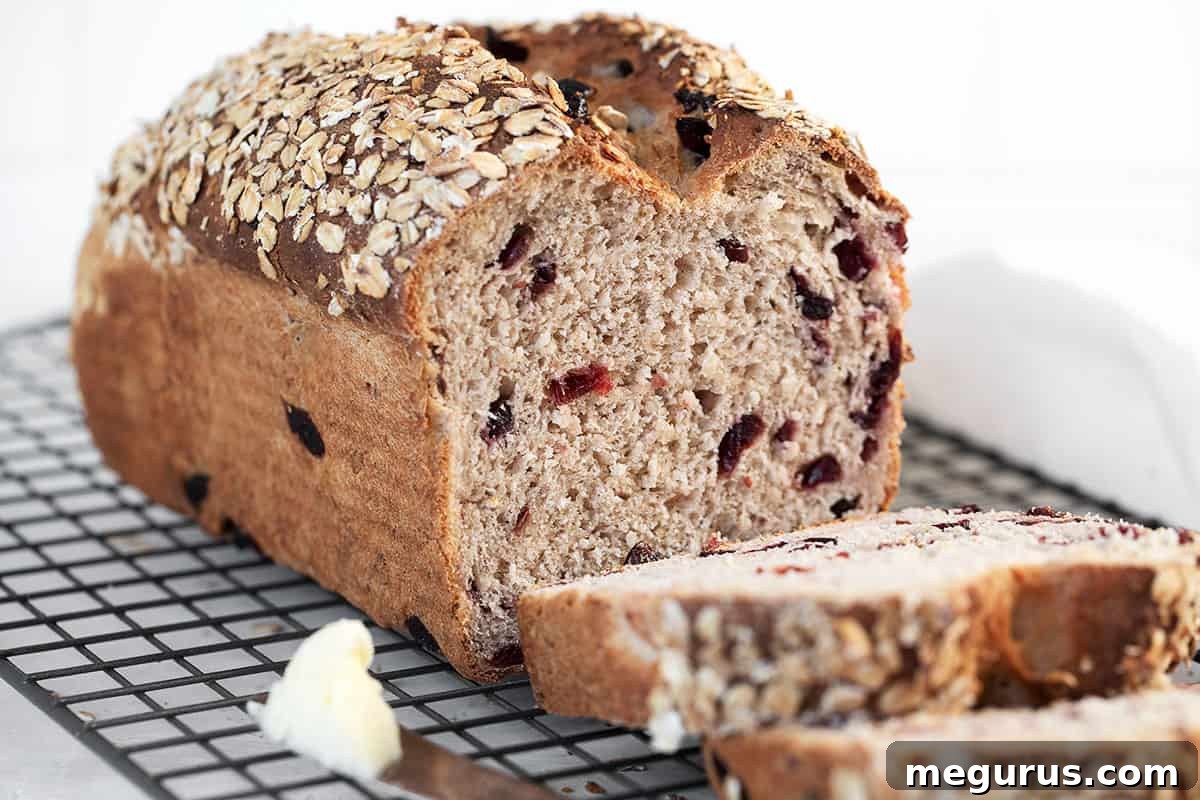 Freshly baked cranberry oatmeal bread, perfectly sliced on a wire cooling rack, showcasing its moist interior and vibrant cranberries.
