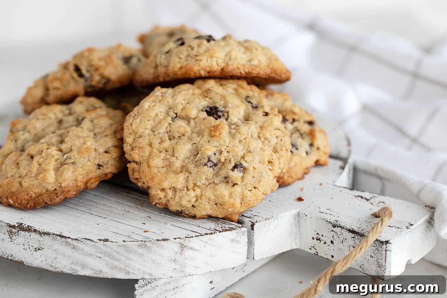 Delightful old-fashioned oatmeal raisin cookies artfully arranged on a rustic serving board, showcasing their golden-brown edges and chewy texture, ready to be enjoyed.