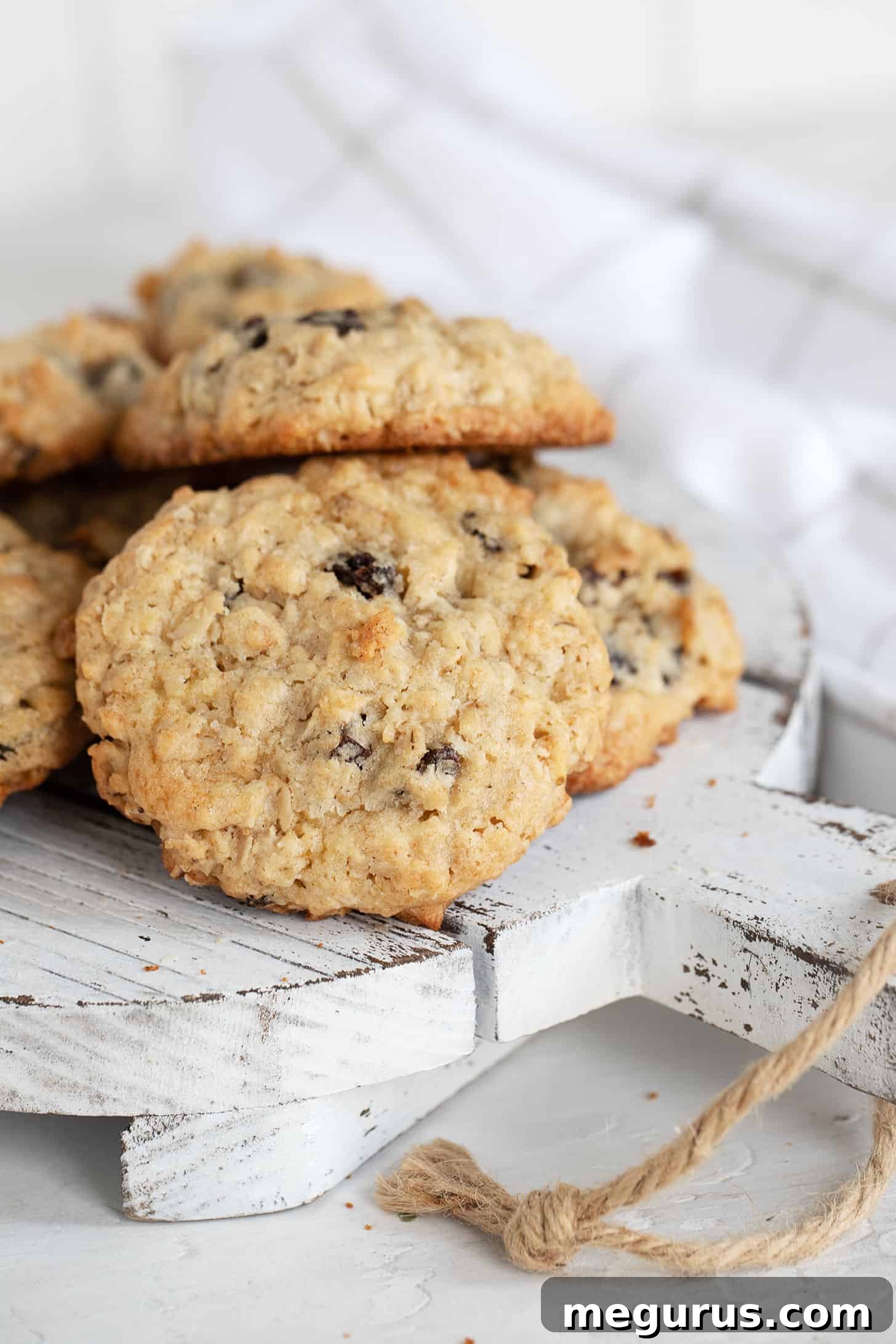 Close-up of a stack of perfectly baked old-fashioned oatmeal raisin cookies, showcasing their inviting texture and golden hue, ready to be devoured.