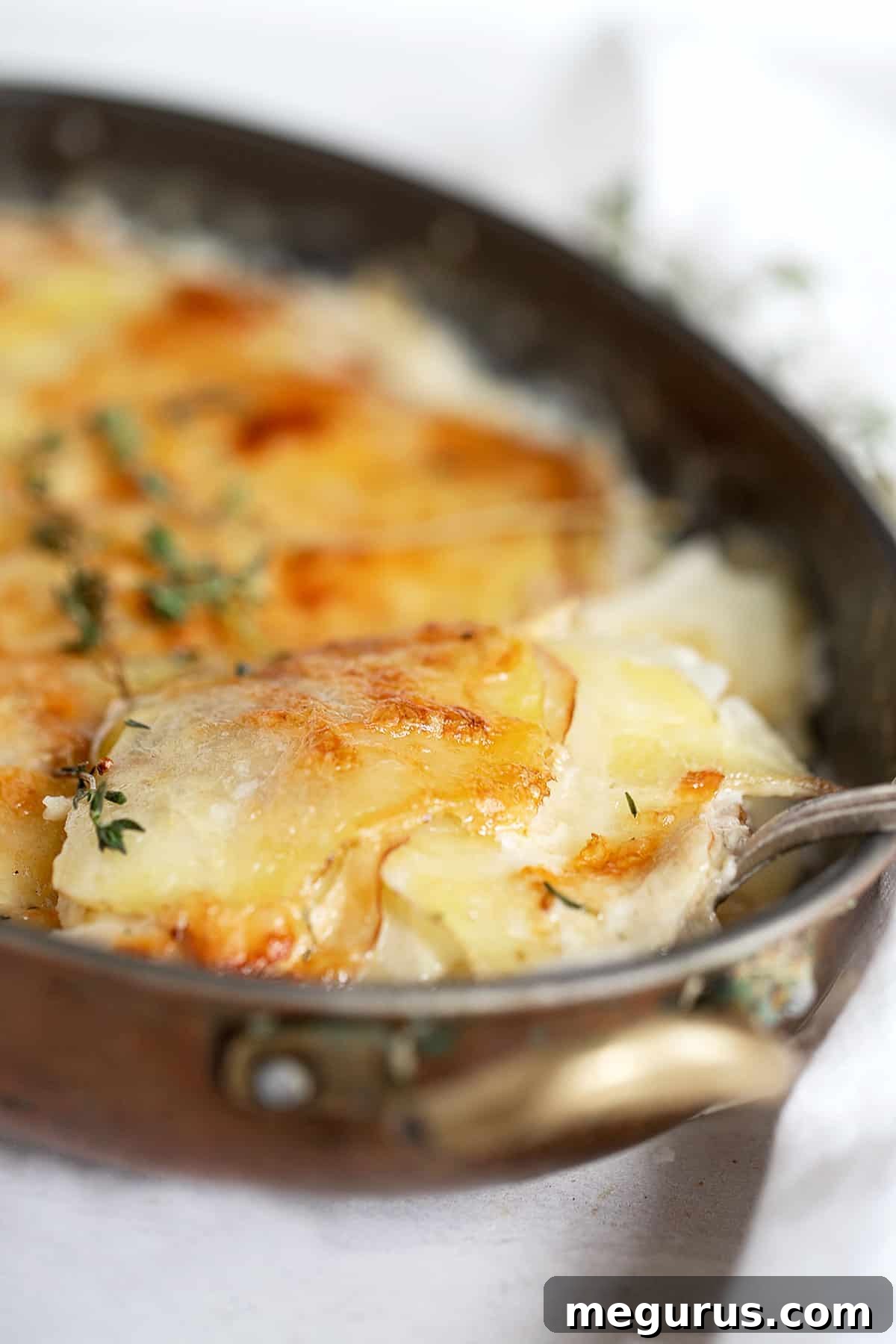 Close-up of baked pear gruyere potato gratin, showing the golden crust and creamy interior