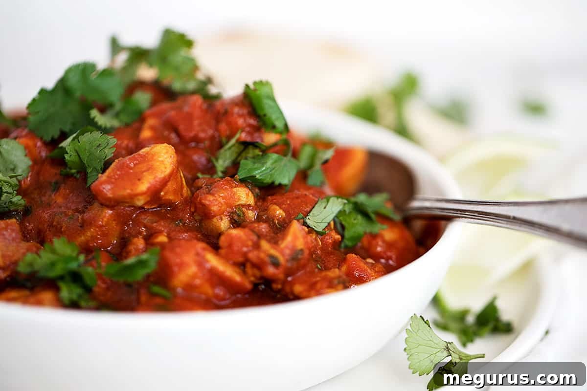 chicken madras in white bowl with lime and naan