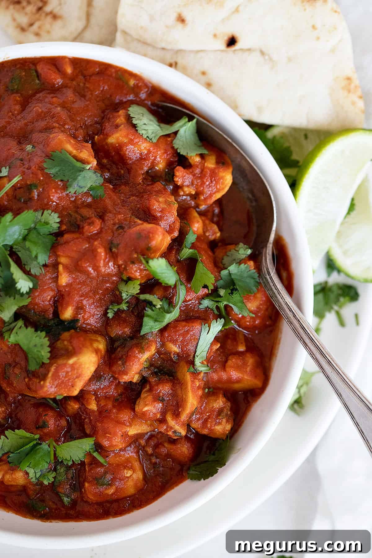 chicken madras in white bowl with lime and naan
