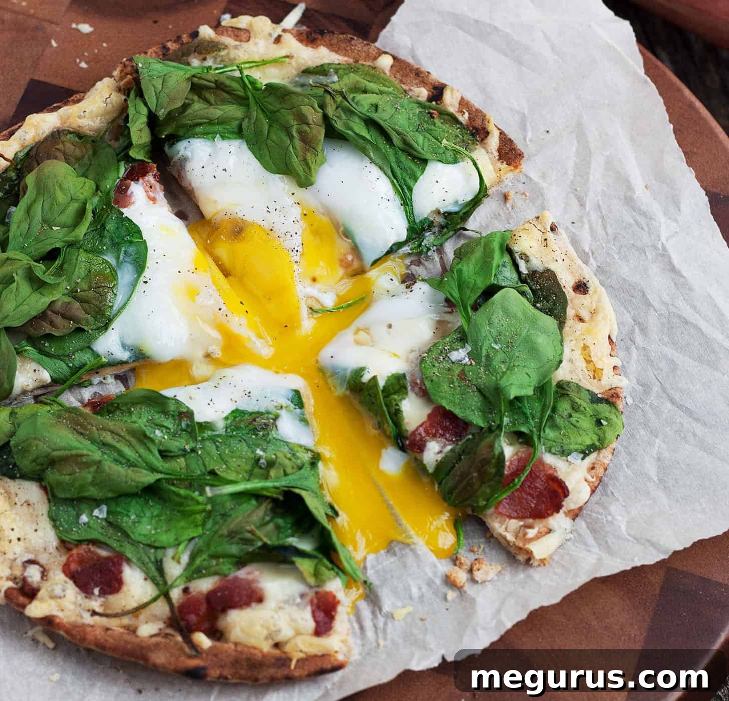 Sliced breakfast pita pizza with runny egg yolk on parchment paper, ready to serve.