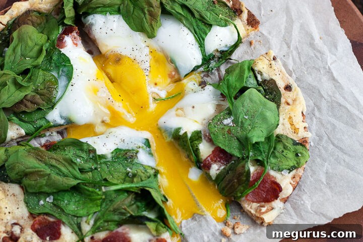 Breakfast pita pizza cut on parchment paper, showing crispy crust and egg yolk.
