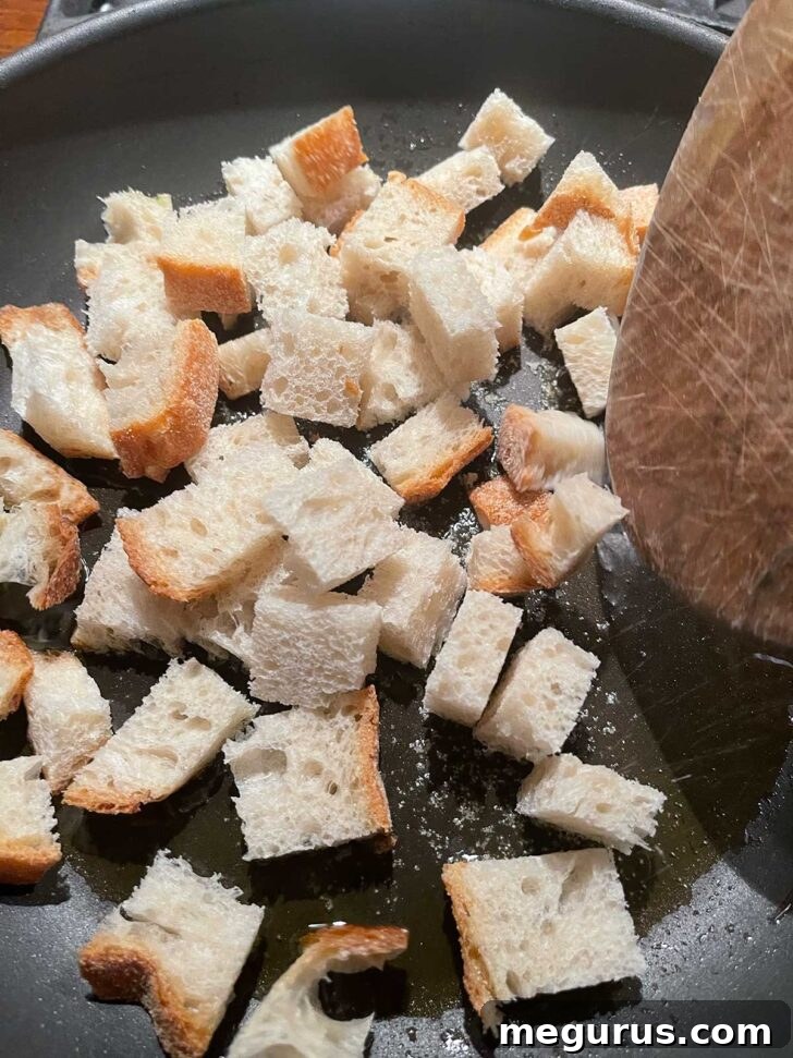 Browning bread cubes in a skillet for homemade croutons.