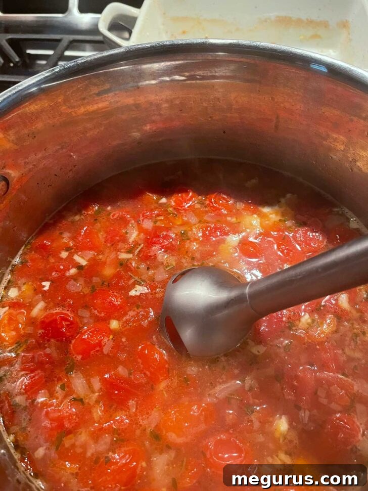 Using an immersion blender to puree the soup to a smooth consistency.