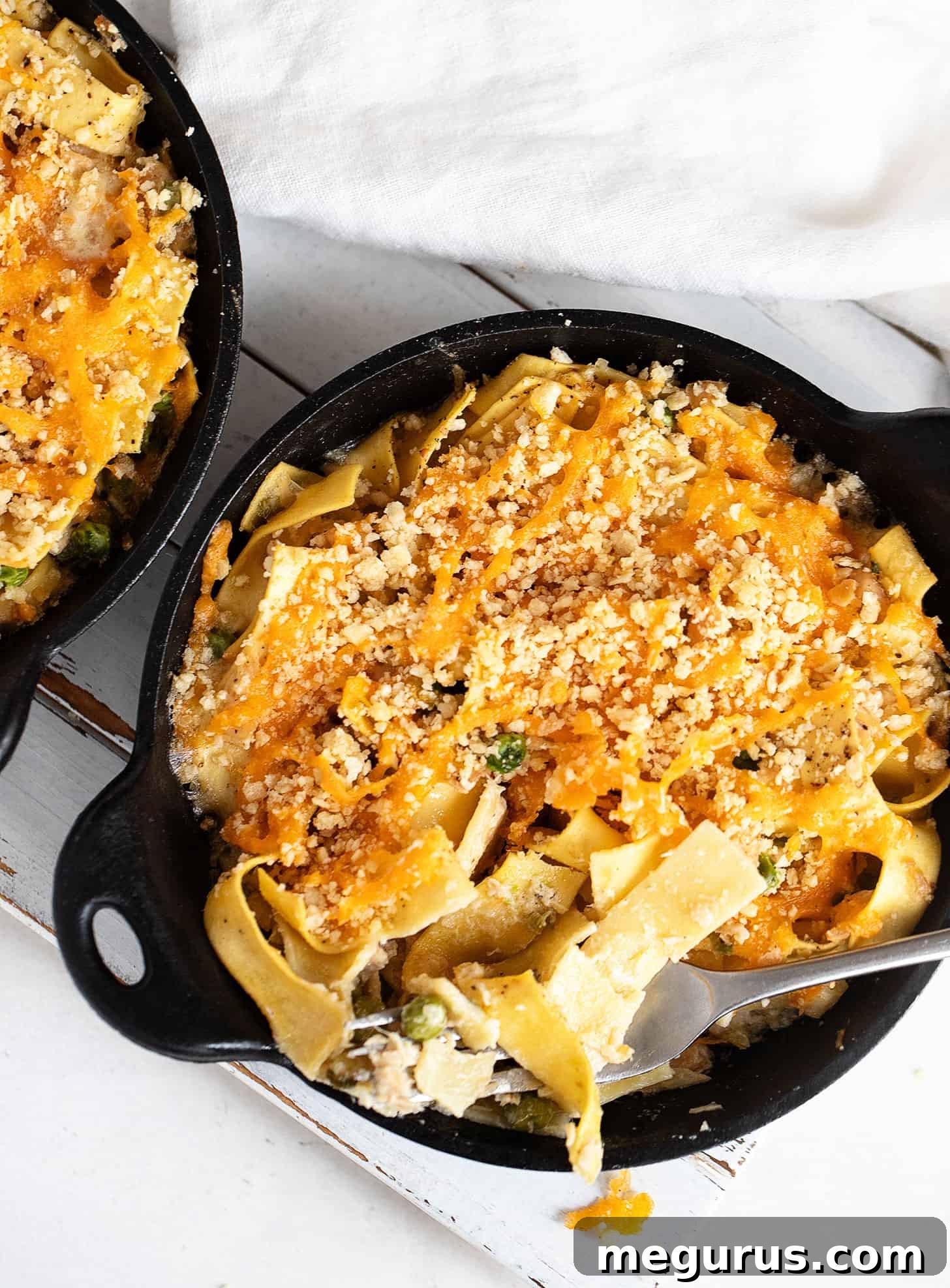 Close-up of golden-brown tuna casserole in two mini cast iron skillets