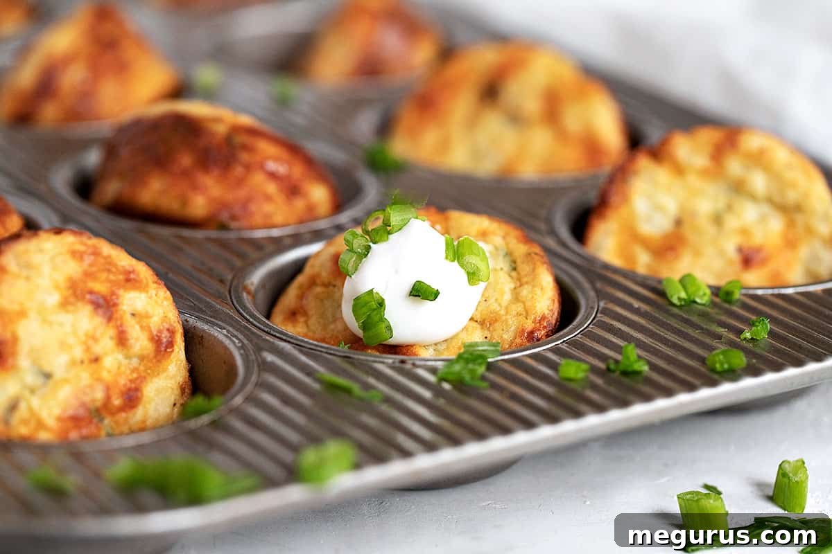 Crispy Muffin Tin Mashed Potatoes in a muffin tin, garnished with sour cream and fresh green onions, ready to serve.