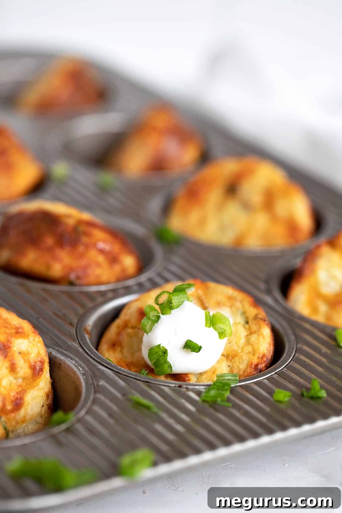 Close-up of baked Muffin Tin Mashed Potatoes, golden and inviting, ready to be lifted from the tin.