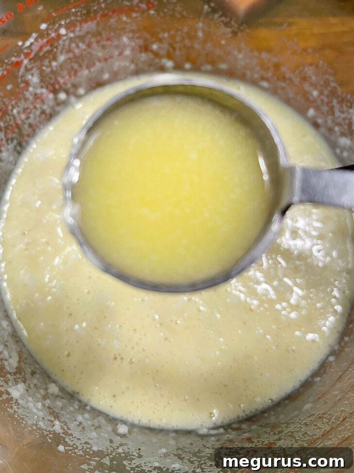 Stirring melted butter into the mashed potato mixture.