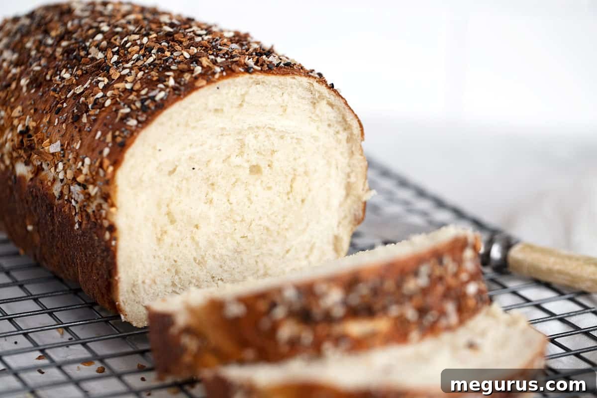 Freshly baked bagel bread, perfectly sliced and cooling on a wire rack, showcasing its chewy crust and soft interior.
