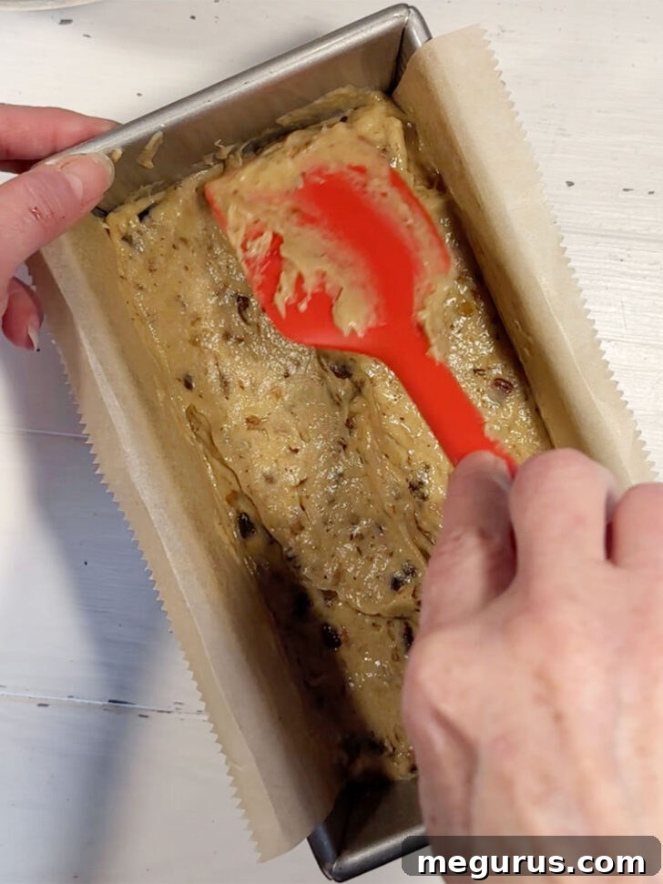 The date nut bread batter being spread evenly into the prepared loaf pan.