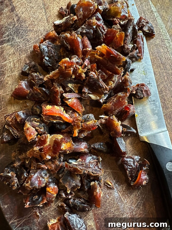 Dried dates being chopped on a wooden cutting board.