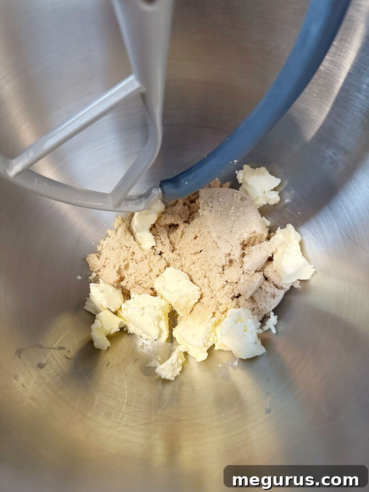Room temperature butter and brown sugar being creamed in a mixing bowl.