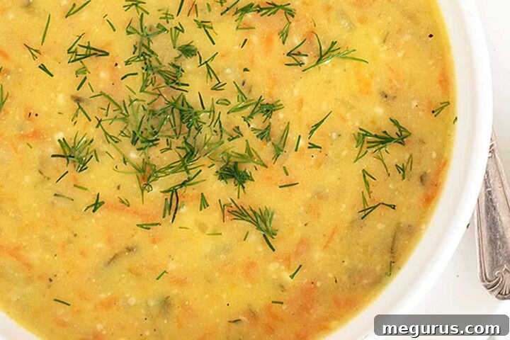 Polish potato and dill pickle soup in white bowl with spoon