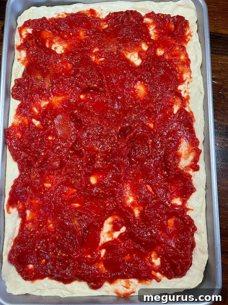 Homemade tomato sauce spread evenly onto the pizza dough.
