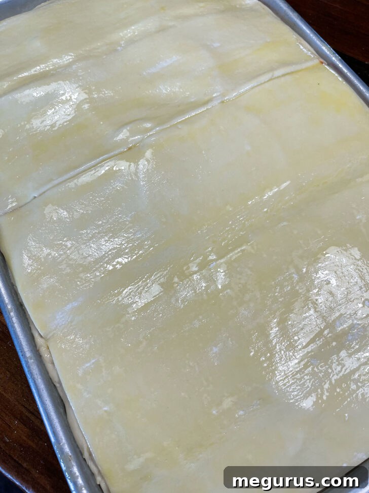 Puff pastry carefully laid on top of the assembled pizza parigina, covering the filling.