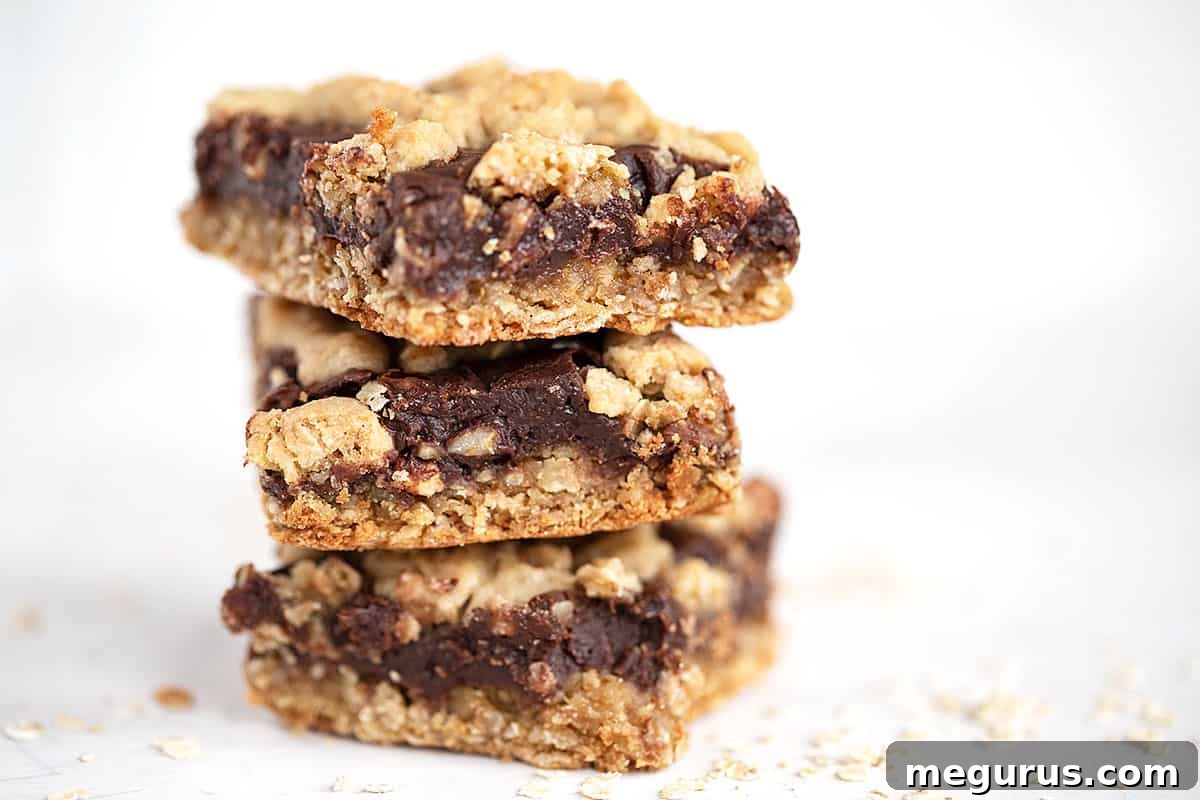 Chocolate oatmeal bars cut and stacked on a white surface.