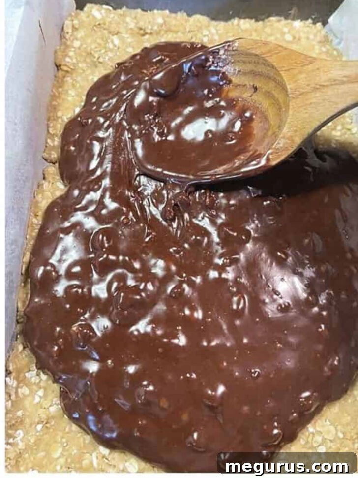 Pouring the melted chocolate filling over the pressed oatmeal base.