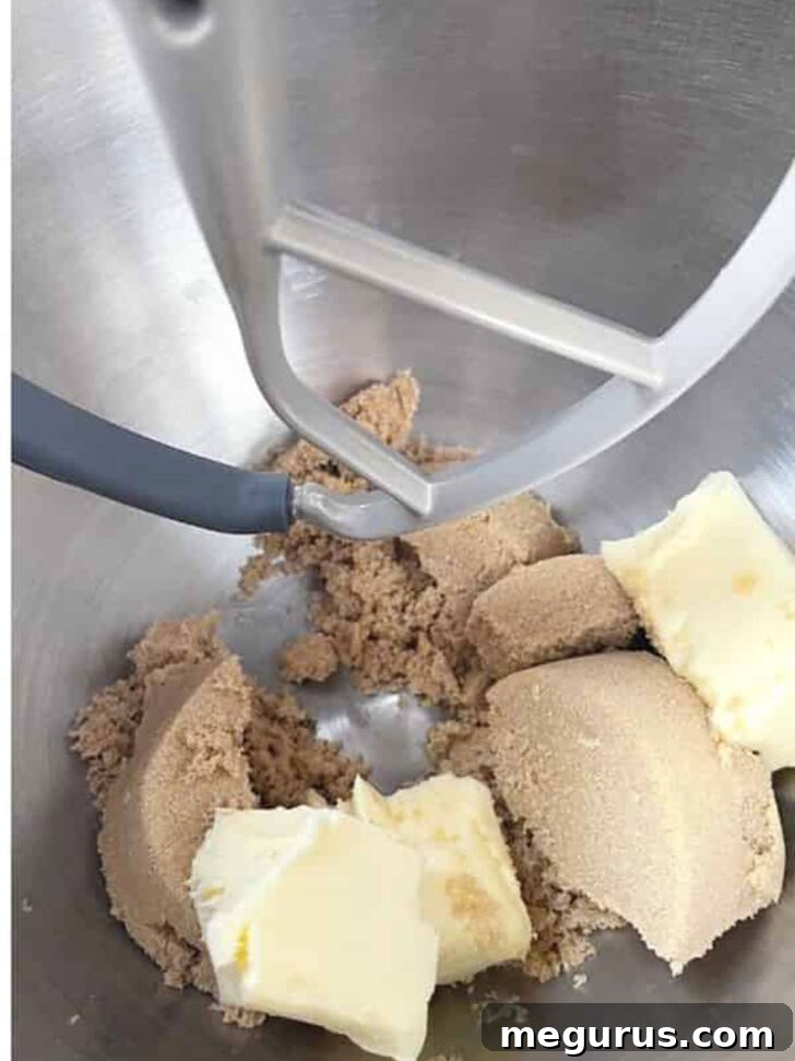 Butter and brown sugar creaming together in a mixing bowl.