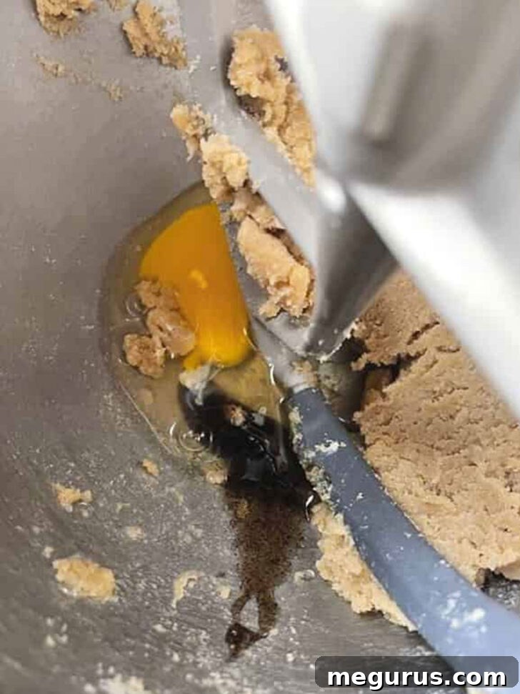 Adding a large egg to the creamed butter and sugar mixture.