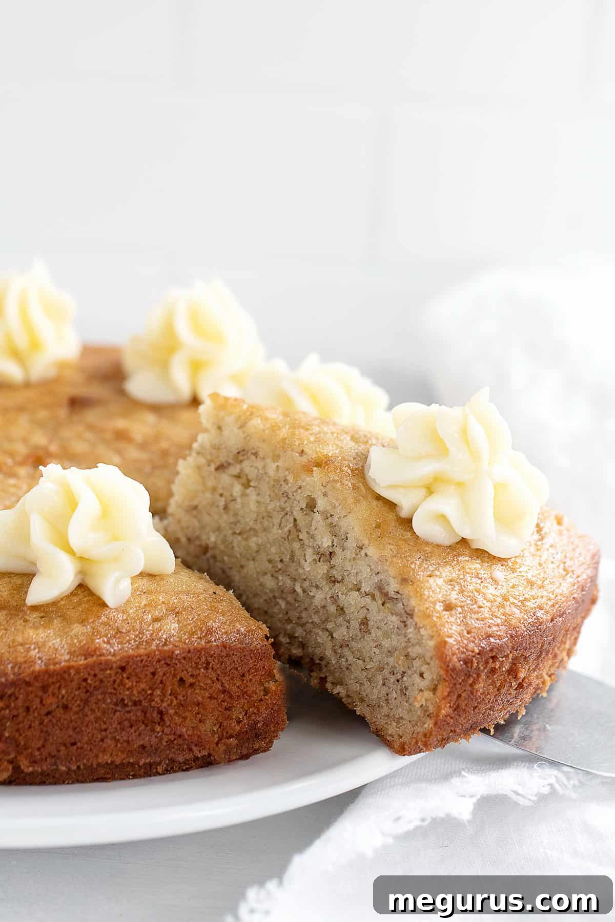 Close-up of a generously frosted slice of banana snack cake with cream cheese frosting